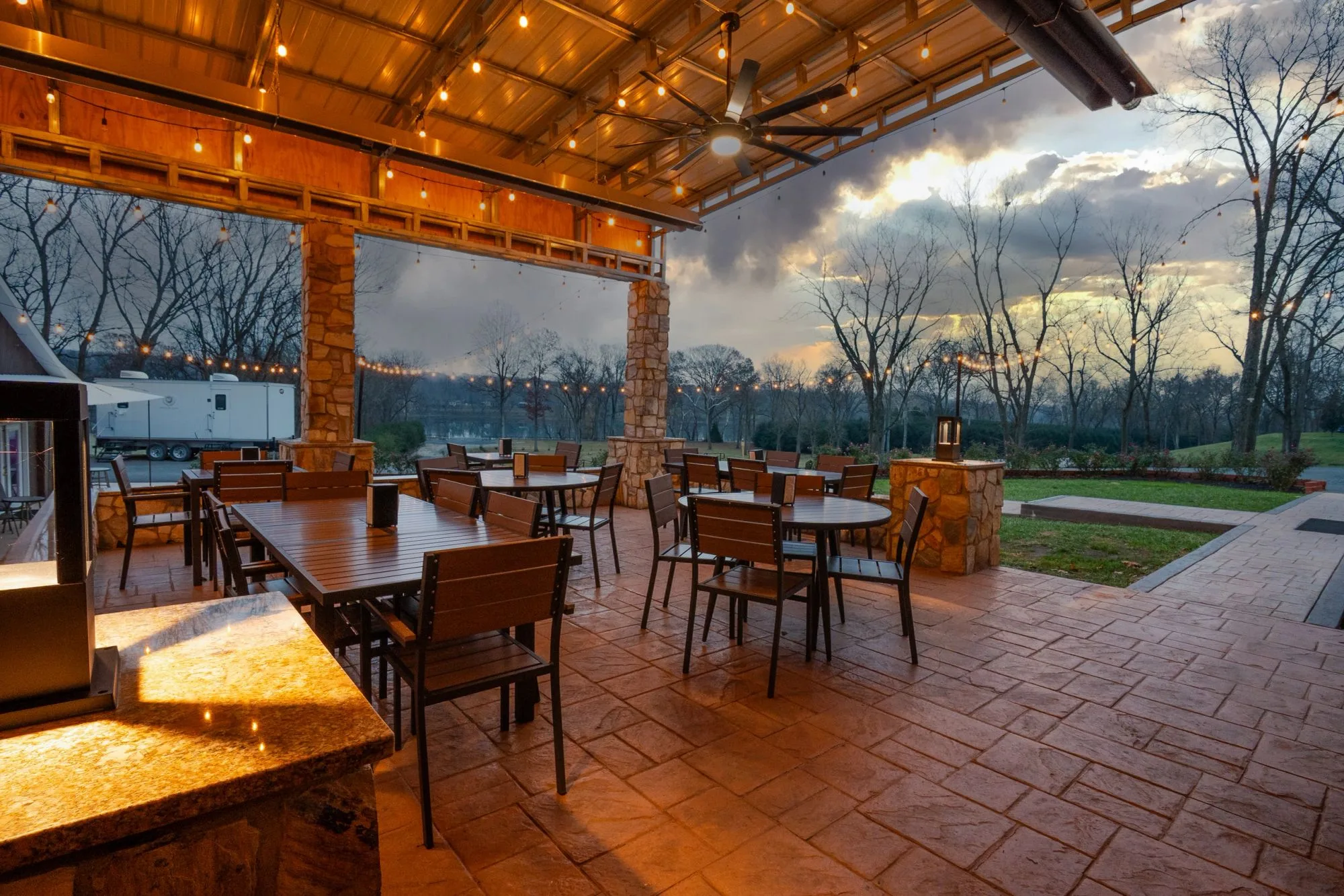 The covered patio at Whites Ferry Brewery glowing with string lights at dusk over the Potomac